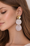 Close-up of a woman wearing a gold and pink earrings.
