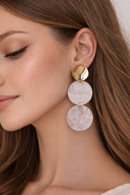 Close-up of a woman wearing a gold and pink earrings.