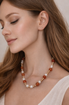 Woman wearing a pearl and brown bead necklace with a neutral background