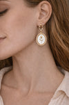 Close-up of a woman wearing gold earrings with a rose design.