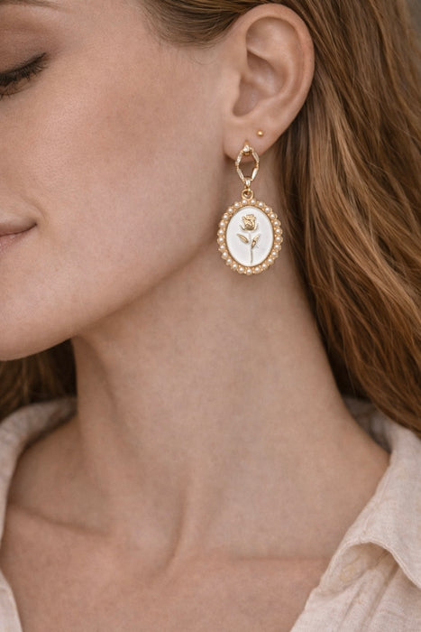 Close-up of a woman wearing gold earrings with a rose design.