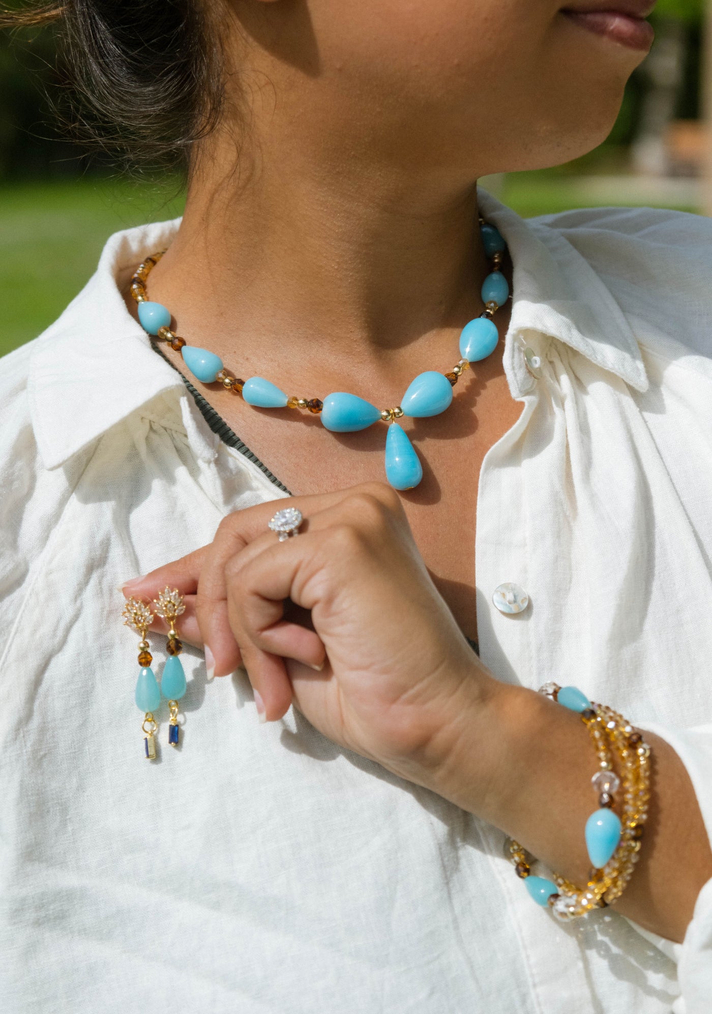 Person wearing turquoise beaded jewelry with a blurred green background