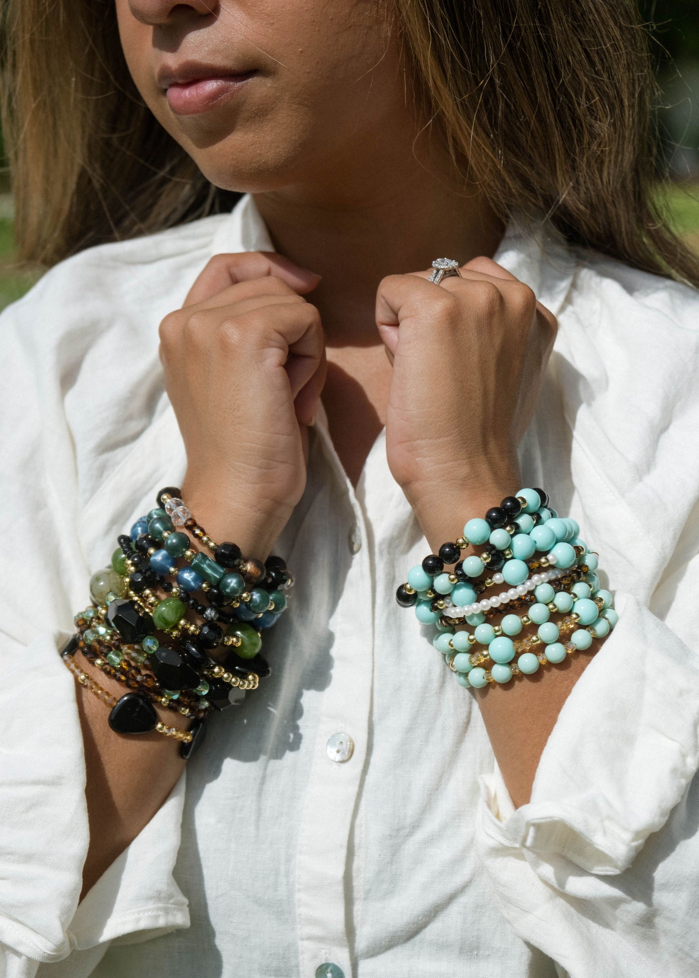 Person wearing multiple beaded bracelets on a white shirt