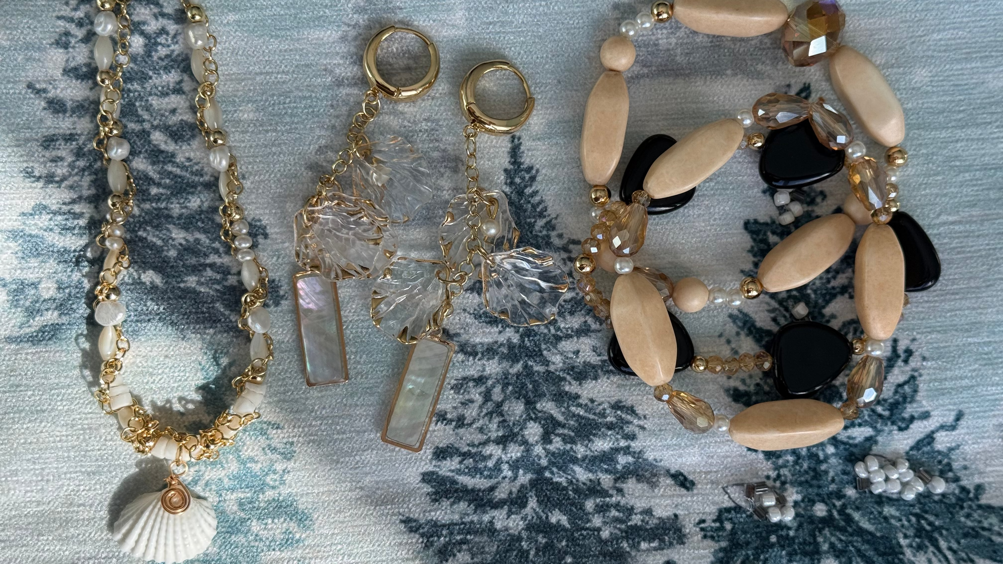 Jewelry set including a necklace, earrings, and bracelet on a textured fabric background