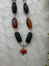 Necklace with black, brown, and white beads on a textured white background