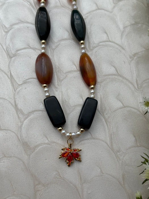 Necklace with black, brown, and white beads on a textured white background
