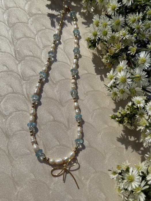 Necklace with white flowers and greenery on a textured surface