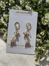 Gold-plated bow-shaped earrings on a card with floral background
