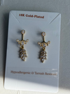 Gold-plated earrings on a clear card with text about material and characteristics.