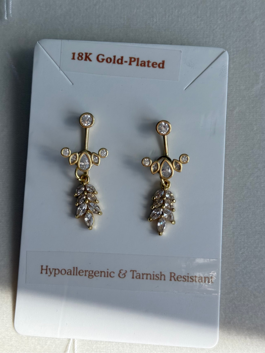 Gold-plated earrings on a clear card with text about material and characteristics.