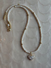 Pearl necklace with a heart-shaped pendant on a textured beige background